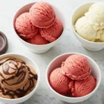 Four bowls of ice cream and sorbet on marble with a Cuisinart lid. Includes chocolate ice cream with sauce, yellow ice cream, and two bowls of red sorbet, showcasing Cuisinart Ice Cream Maker Recipes.